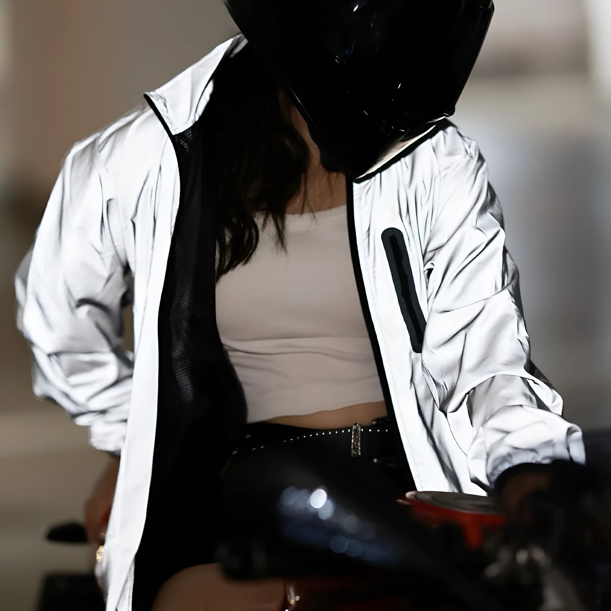 Silver coloured waterproof polyester long sleeved coat with hood on a hanger.