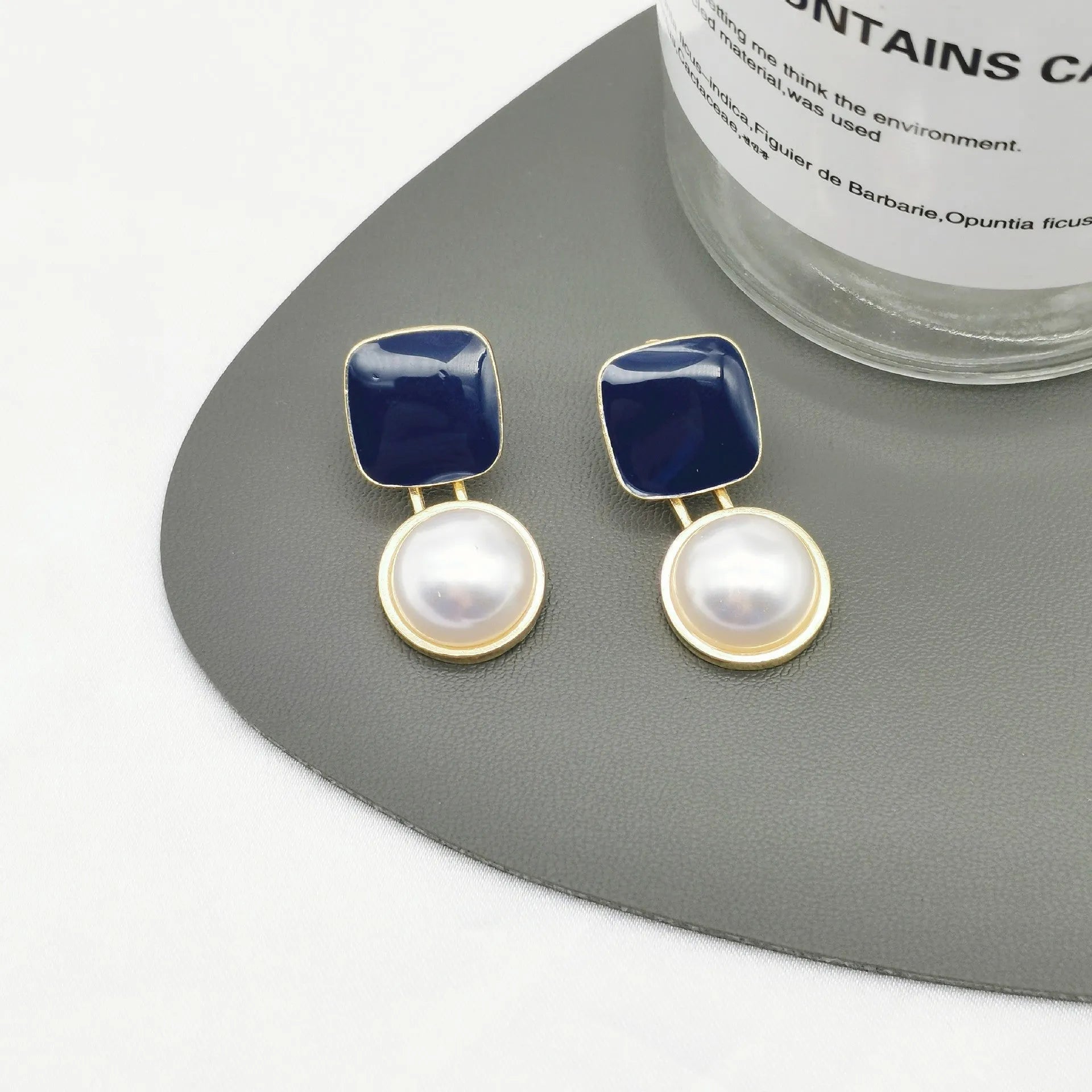 Red geometric alloy stud earrings with pearl centre on white background