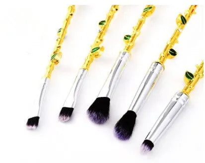 Beauty and the Beast makeup brush set with golden handles and synthetic bristles displayed on a surface