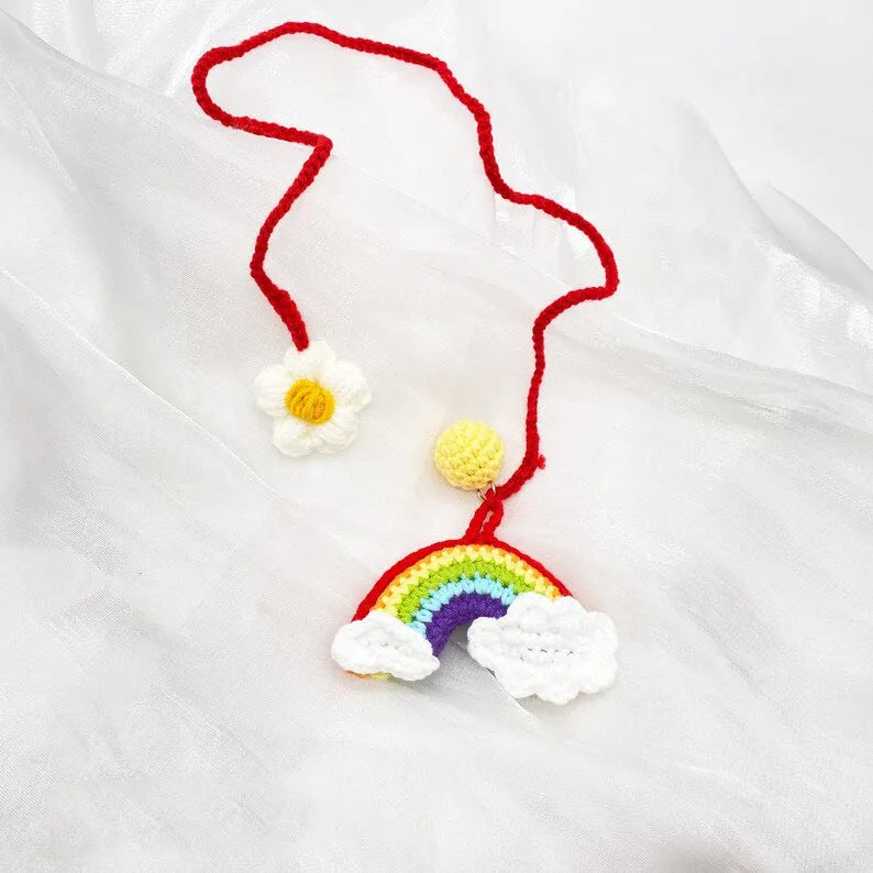 Handmade crocheted wool car pendant shaped like a cartoon avocado with a rainbow flower decoration.