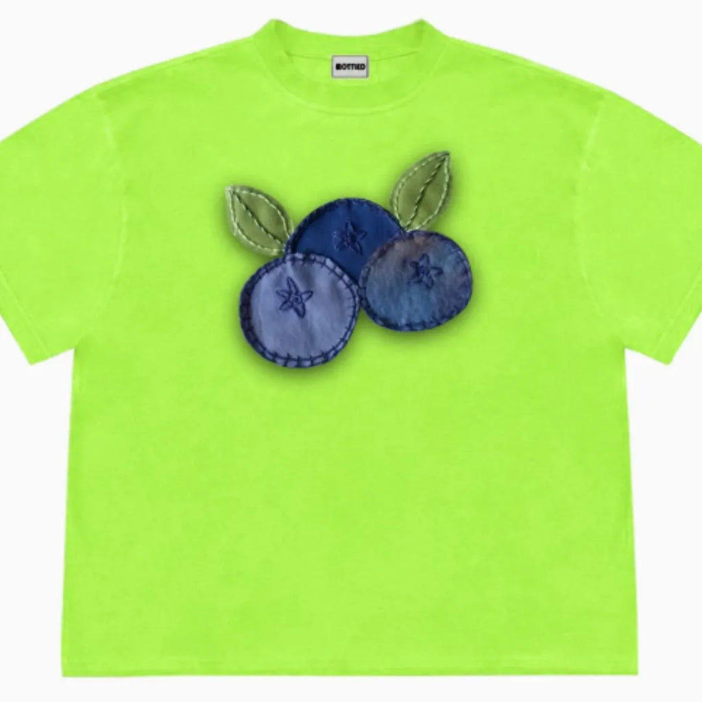 Short sleeved blueberry and fruit patchwork print t-shirt on a hanger.
