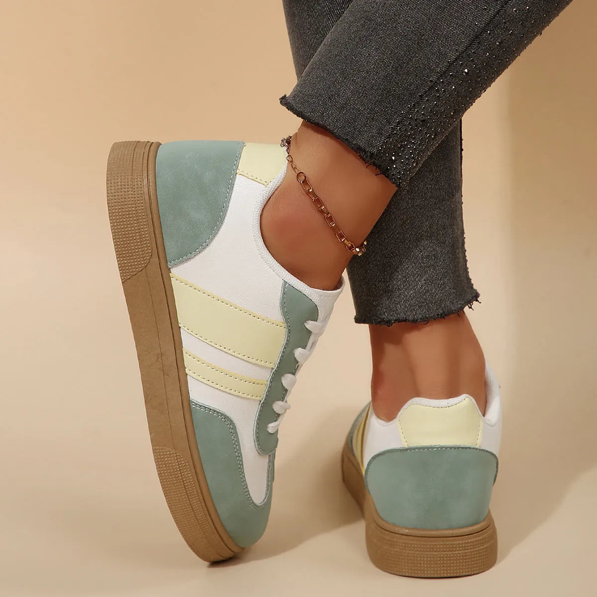 Green women's retro sports shoes with white cross-strap detail and leather stitching on a low rubber sole.
