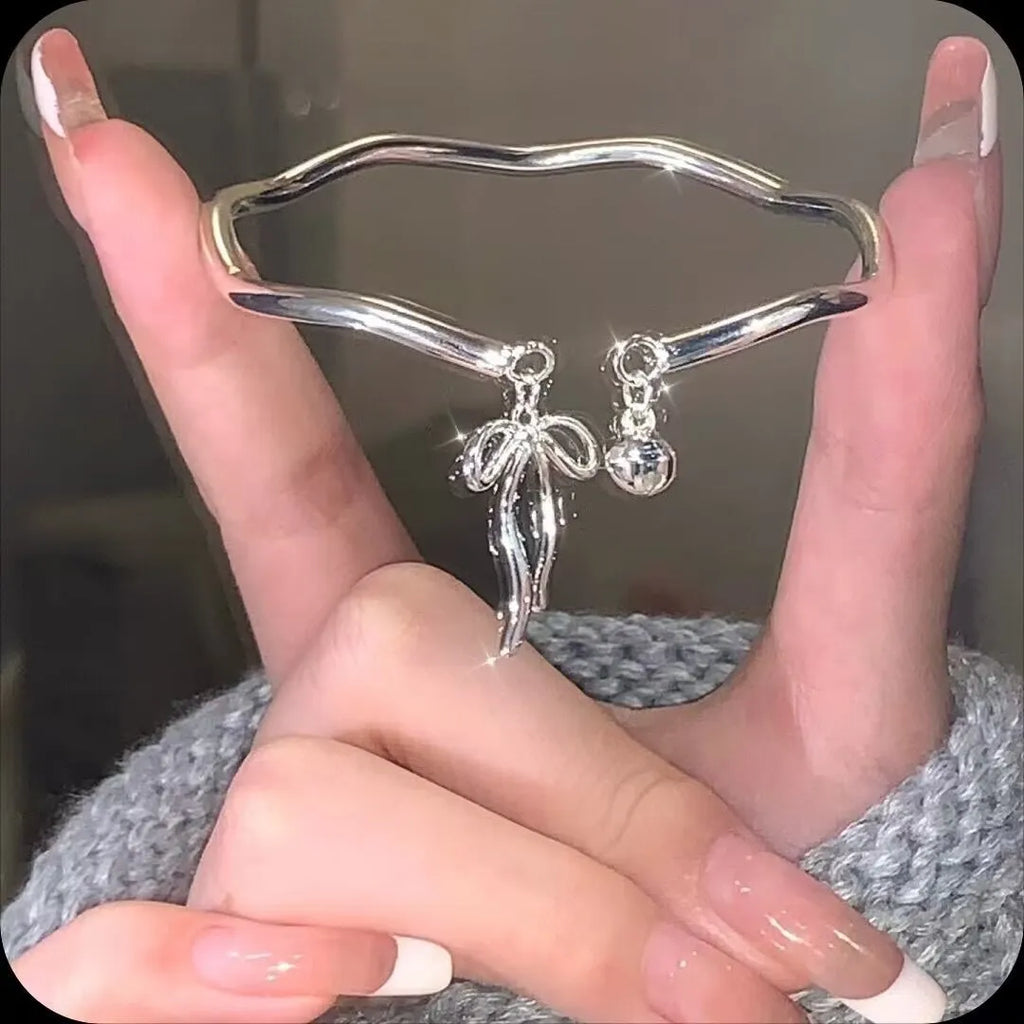 Silver bow adjustable bracelet with bow bell opening clasp on wrist