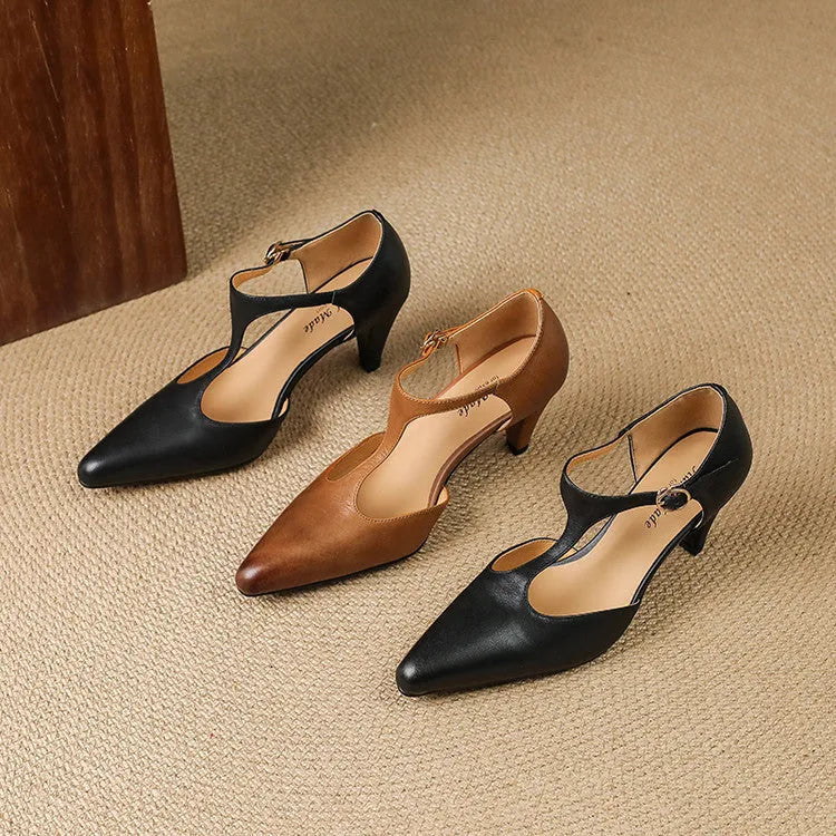 Brown retro women's T-strap sandals with a closed round toe and a short stout heel on a wooden background.