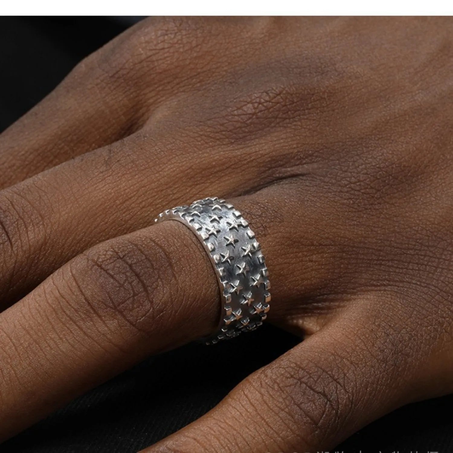 Adjustable silver ring with a geometric pattern of multiple five-pointed stars on a white background.