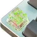 Transparent resin mechanical keyboard keycap with starry sky design in green, pink, red, violet colours.