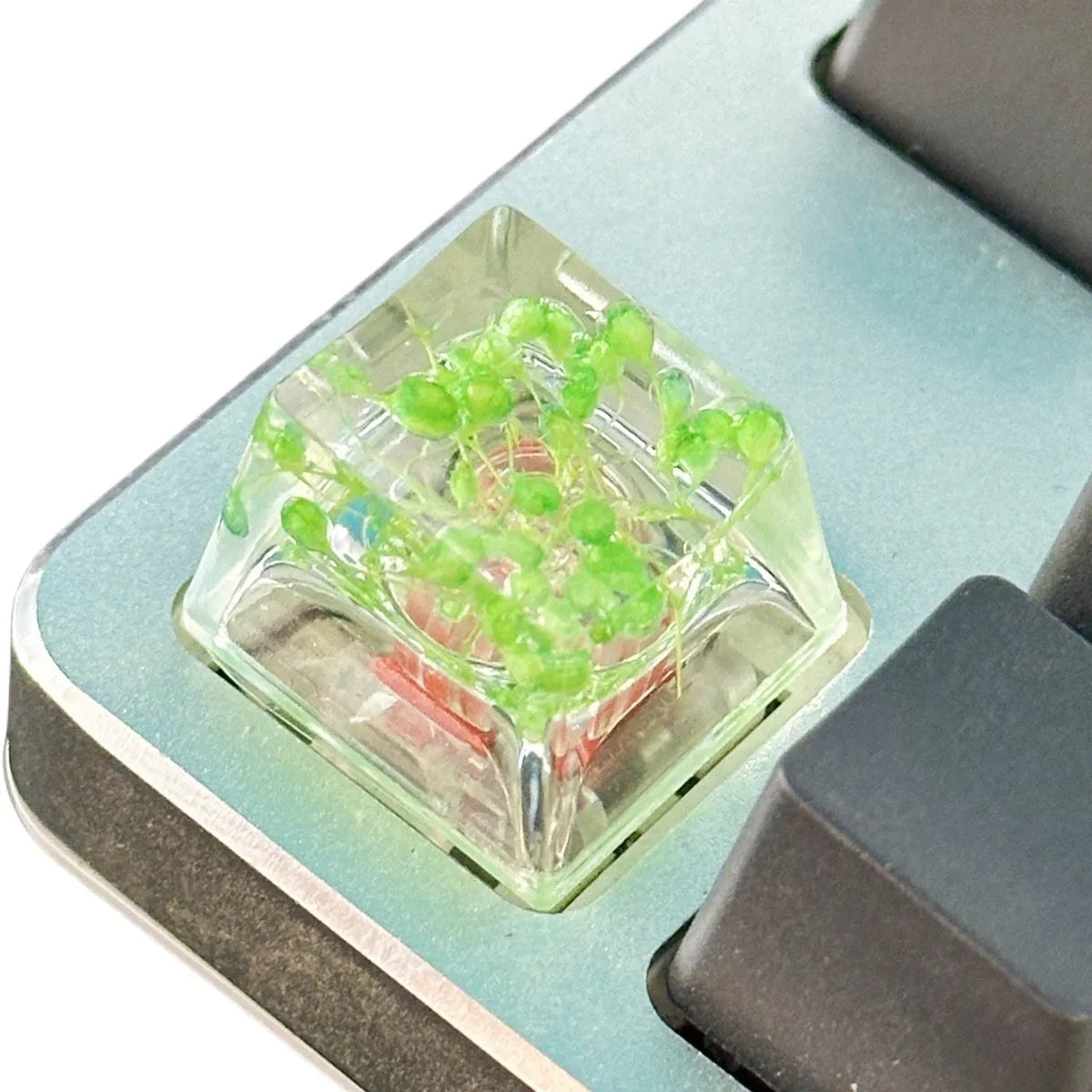 Transparent resin mechanical keyboard keycap with starry sky design in green, pink, red, violet colours.