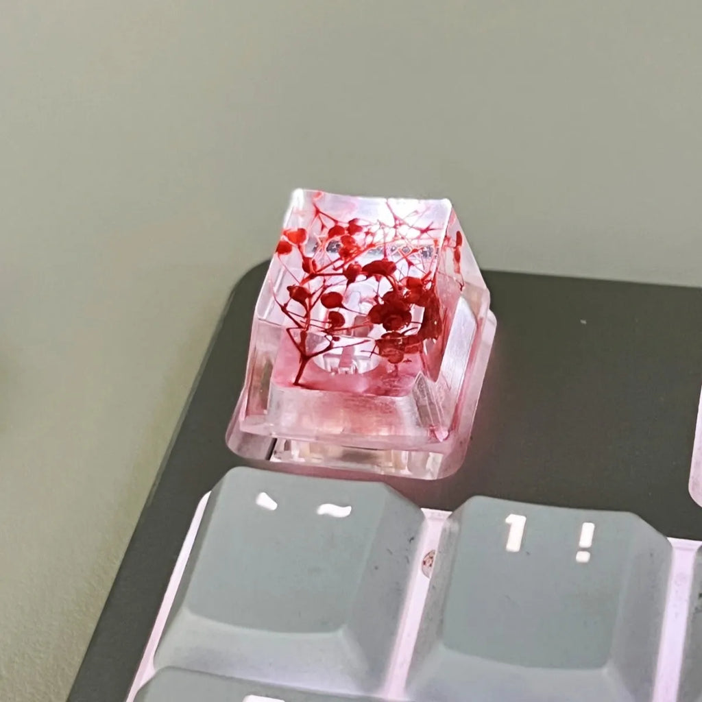 Transparent resin mechanical keyboard keycap with starry sky design in green, pink, red, violet colours.