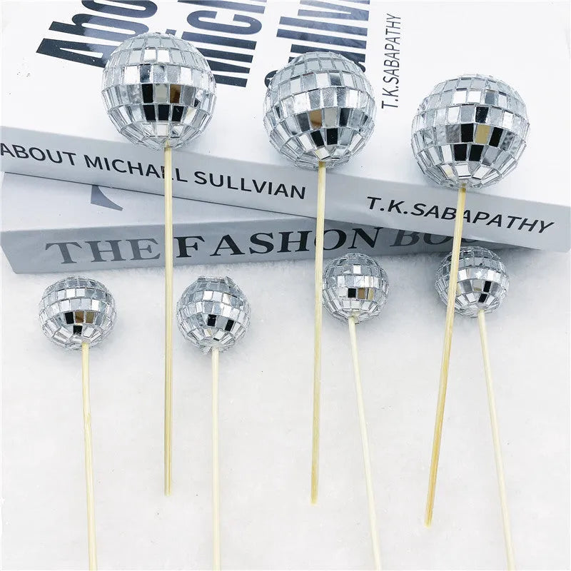 Small glass mirror disco ball on a wooden stick used as a cake decoration