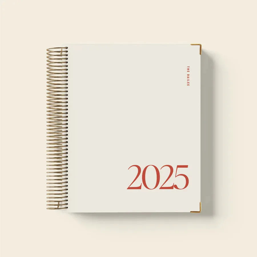 Cherry red coil notebook with daily schedule pages open showing weekly layout