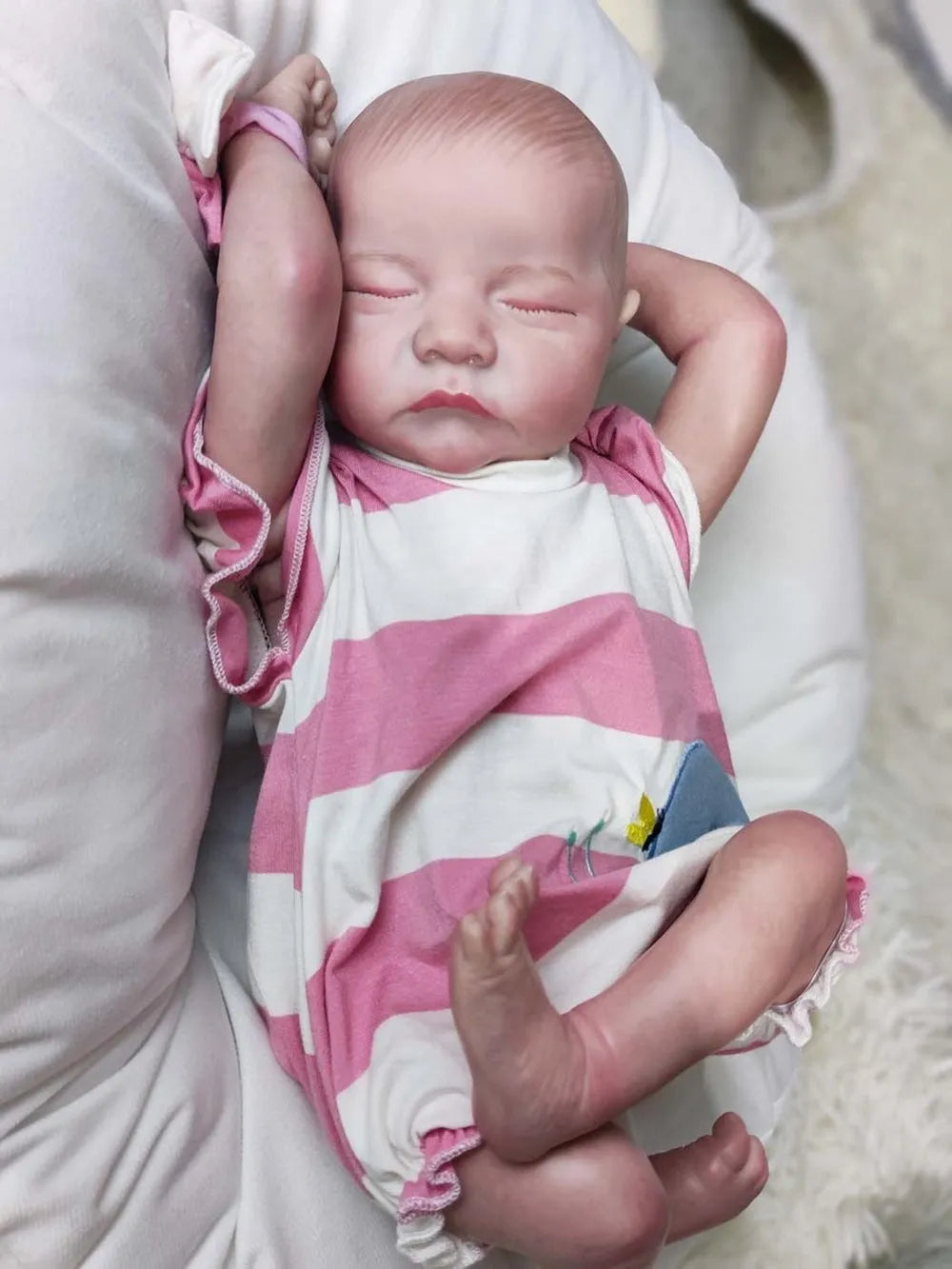 18-inch reborn doll with cloth body in soft pink romper sitting on table