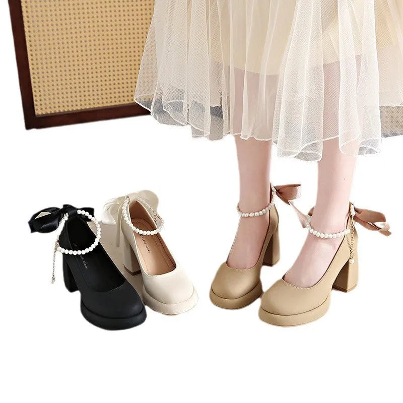 Beige women's Mary Jane shoes with a chunky block heel, ankle strap buckle, and round toe with pearl detail.
