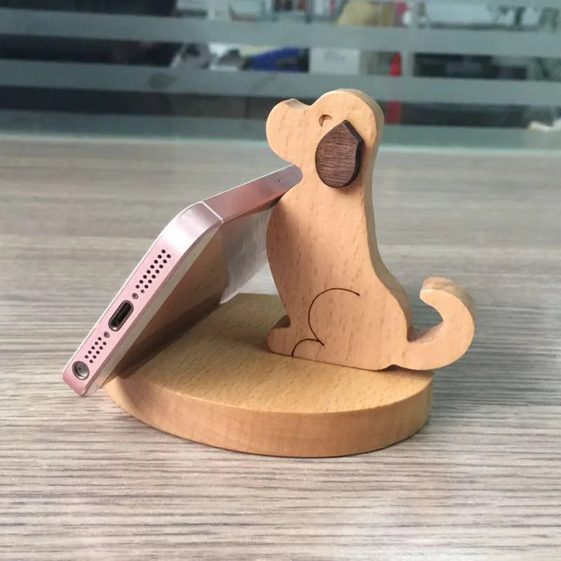 Solid wood cartoon puppy phone bracket with brown spray paint on a desk holding a smartphone upright.
