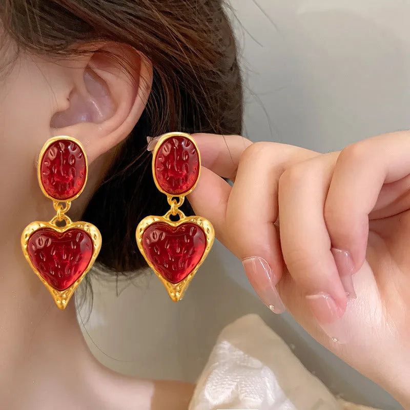 A pair of oval-shaped heart stud earrings with a silver needle texture in purple, red, green, and yellow white colours