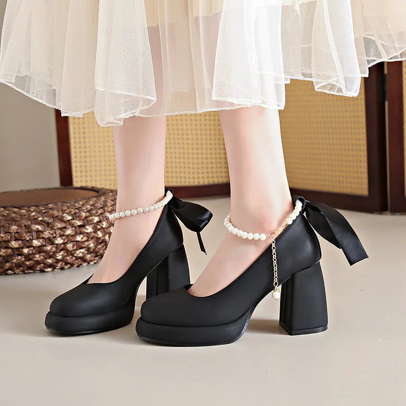 Beige women's Mary Jane shoes with a chunky block heel, ankle strap buckle, and round toe with pearl detail.