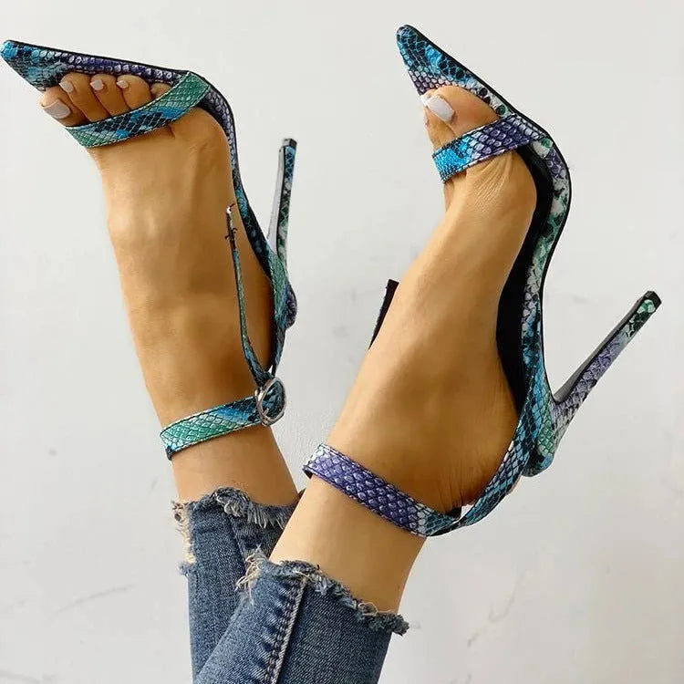 Blue women's high heel pumps with buckle fastening, pointed toe, and hollow out design on a white background.