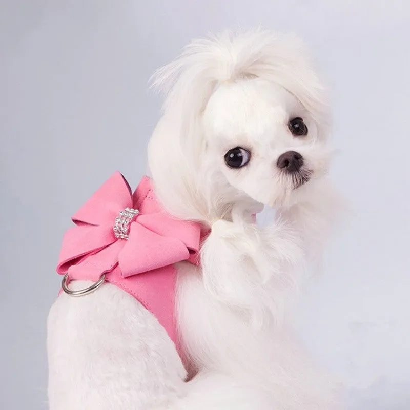 A pink microfiber dog chest strap with a large decorative bowknot, showing leash attachment ring.