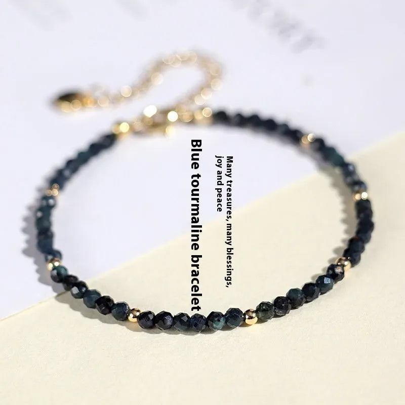 Close-up of a women's bracelet with small blue tourmaline beads and spacer beads on a wrist.