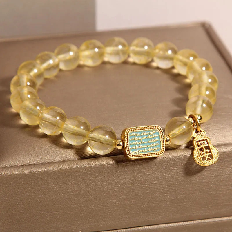 Women's bracelet with yellow citrine stones and sparkling rhinestone details on a white background.