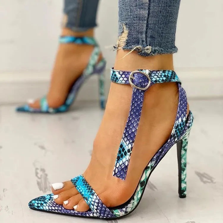Blue women's high heel pumps with buckle fastening, pointed toe, and hollow out design on a white background.