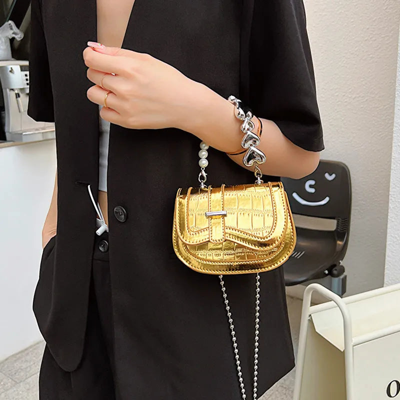 Silver laser pearl finish women's crossbody mini saddle tote bag with single shoulder strap.