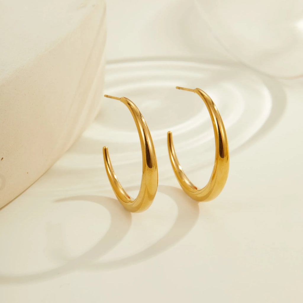 Simple round titanium steel hoop earrings for women in gold and steel finishes, shown in large and small sizes.