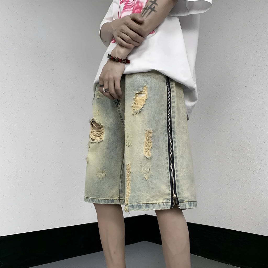 Men's blue loose-fit vintage denim shorts with yellow mud wash and ripped knee details.