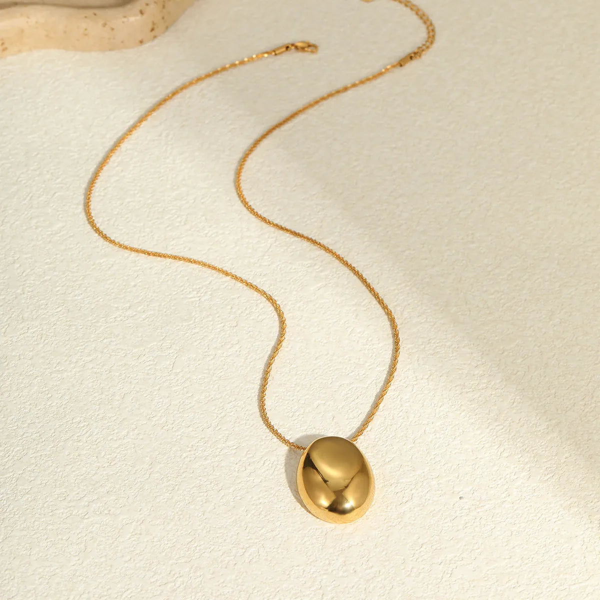 Gold geometric pendant necklace on adjustable chain against white background