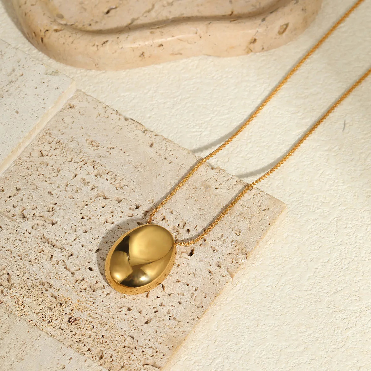 Gold geometric pendant necklace on adjustable chain against white background