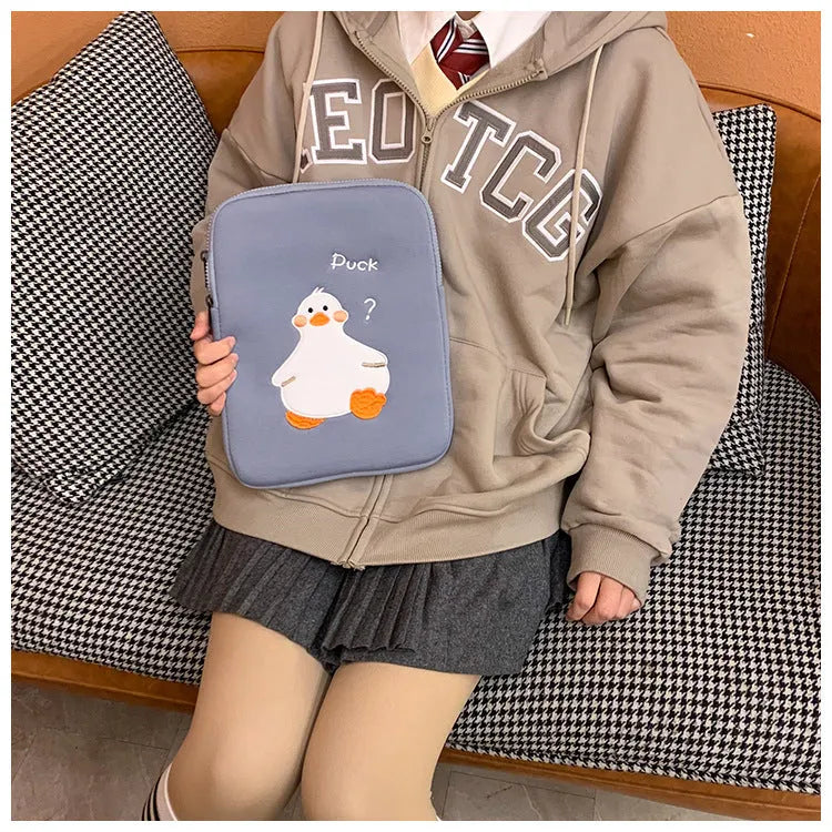 Blue cotton tablet case with embroidered cartoon duck design and a zipper, shown next to a green version.
