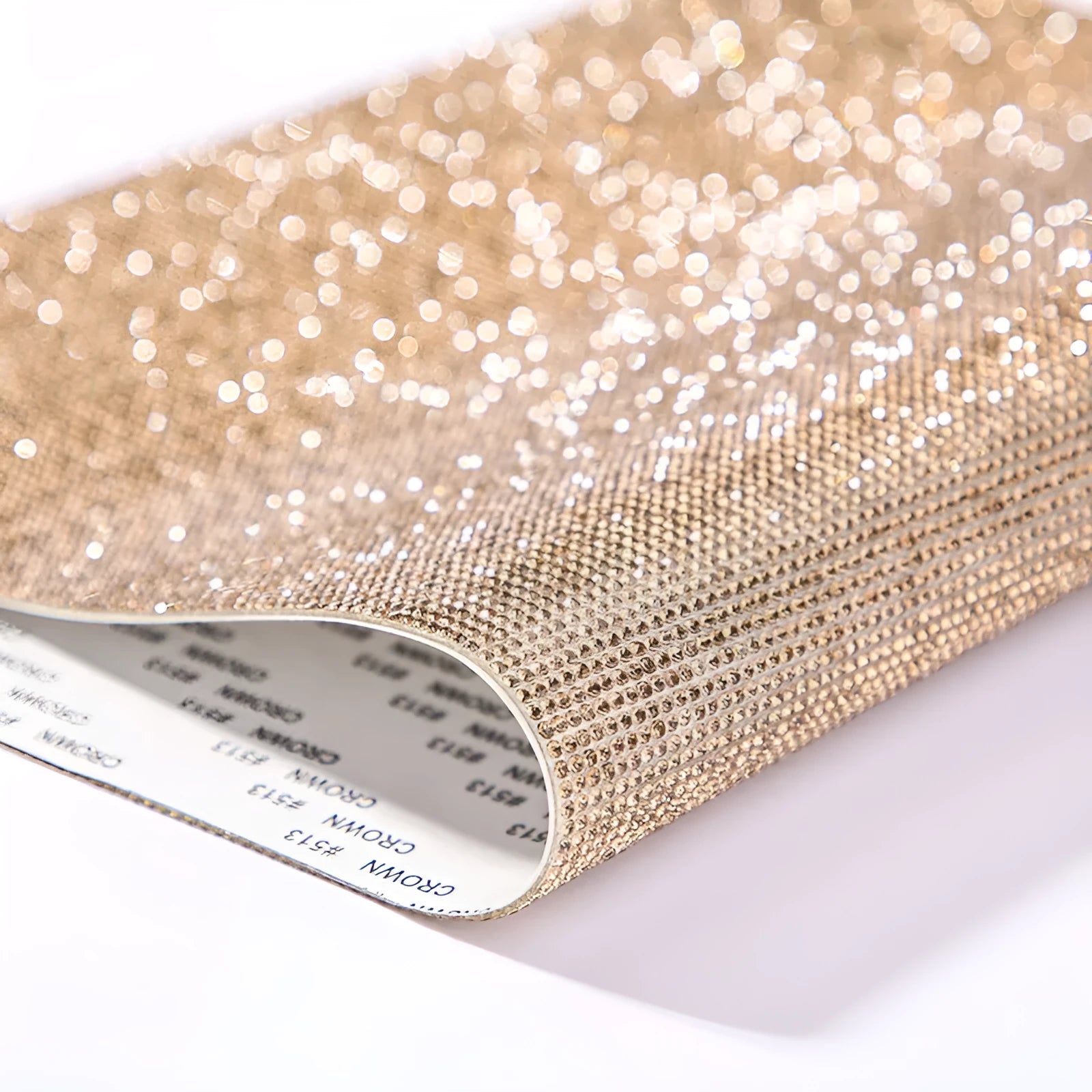 Hot-fix rhinestone transfer sheet on a roll showing sparkling electroplated stones in multiple colours on adhesive backing.