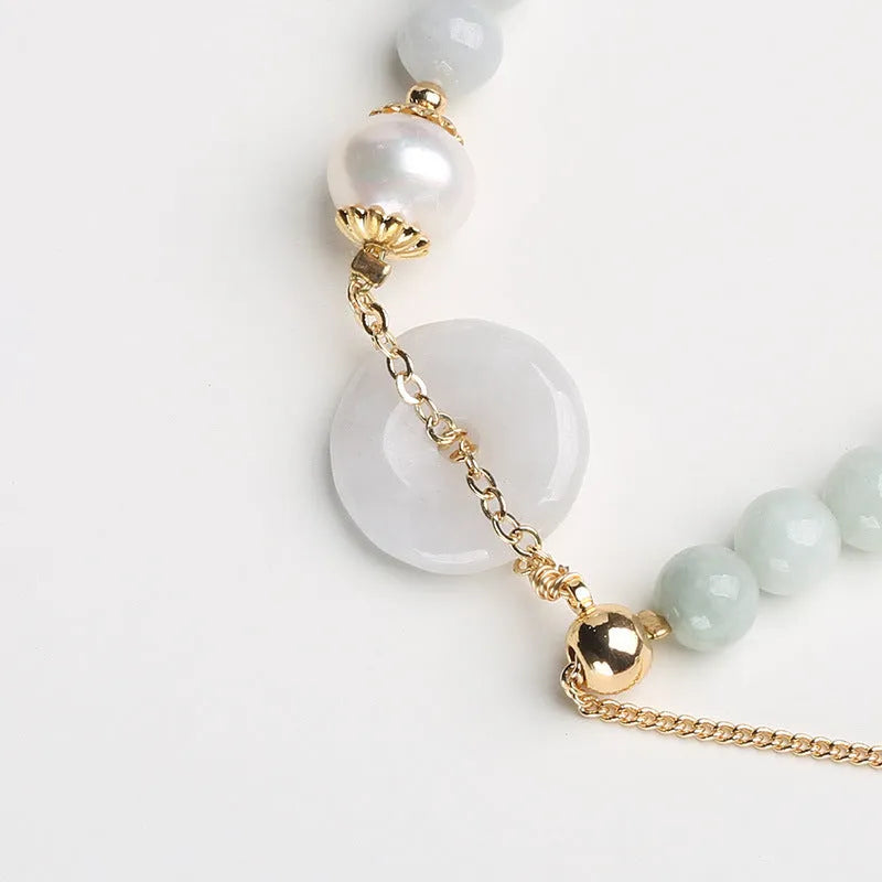 Natural emerald green jade and pearl bracelet with a geometric peace buckle clasp.