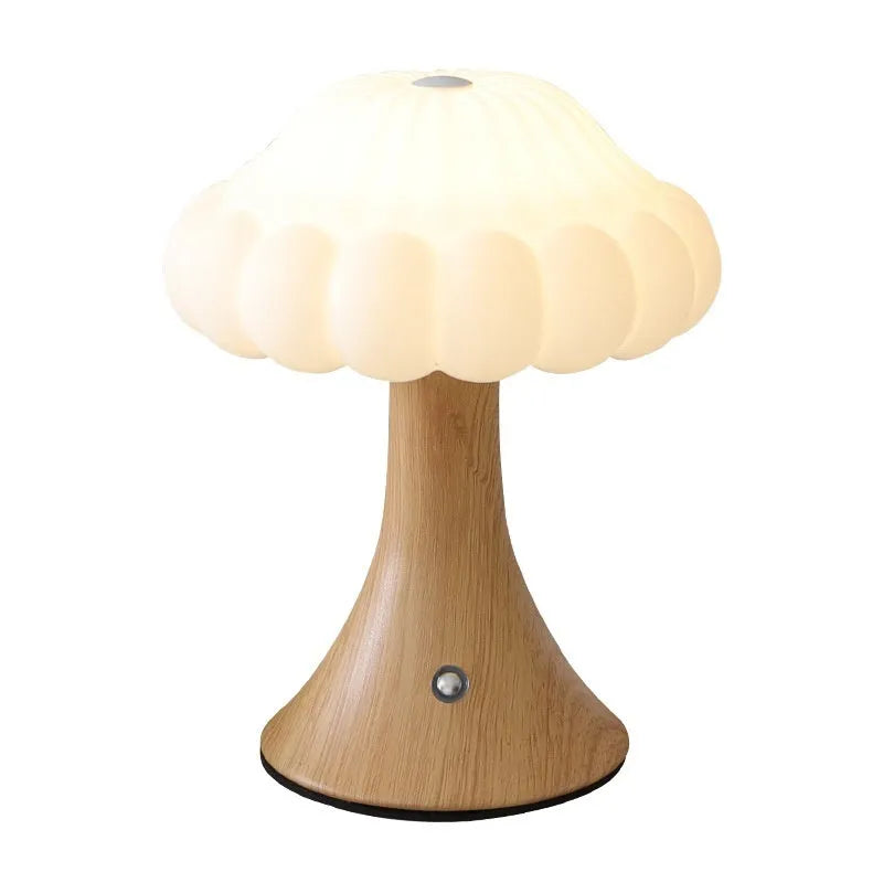 Small mushroom-shaped touch night lamp in wood grain colour on a table.