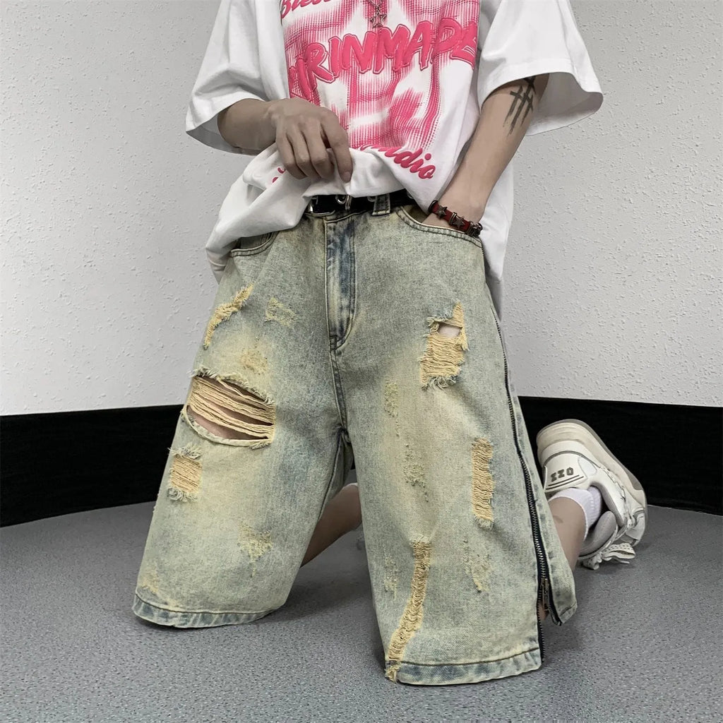 Men's blue loose-fit vintage denim shorts with yellow mud wash and ripped knee details.