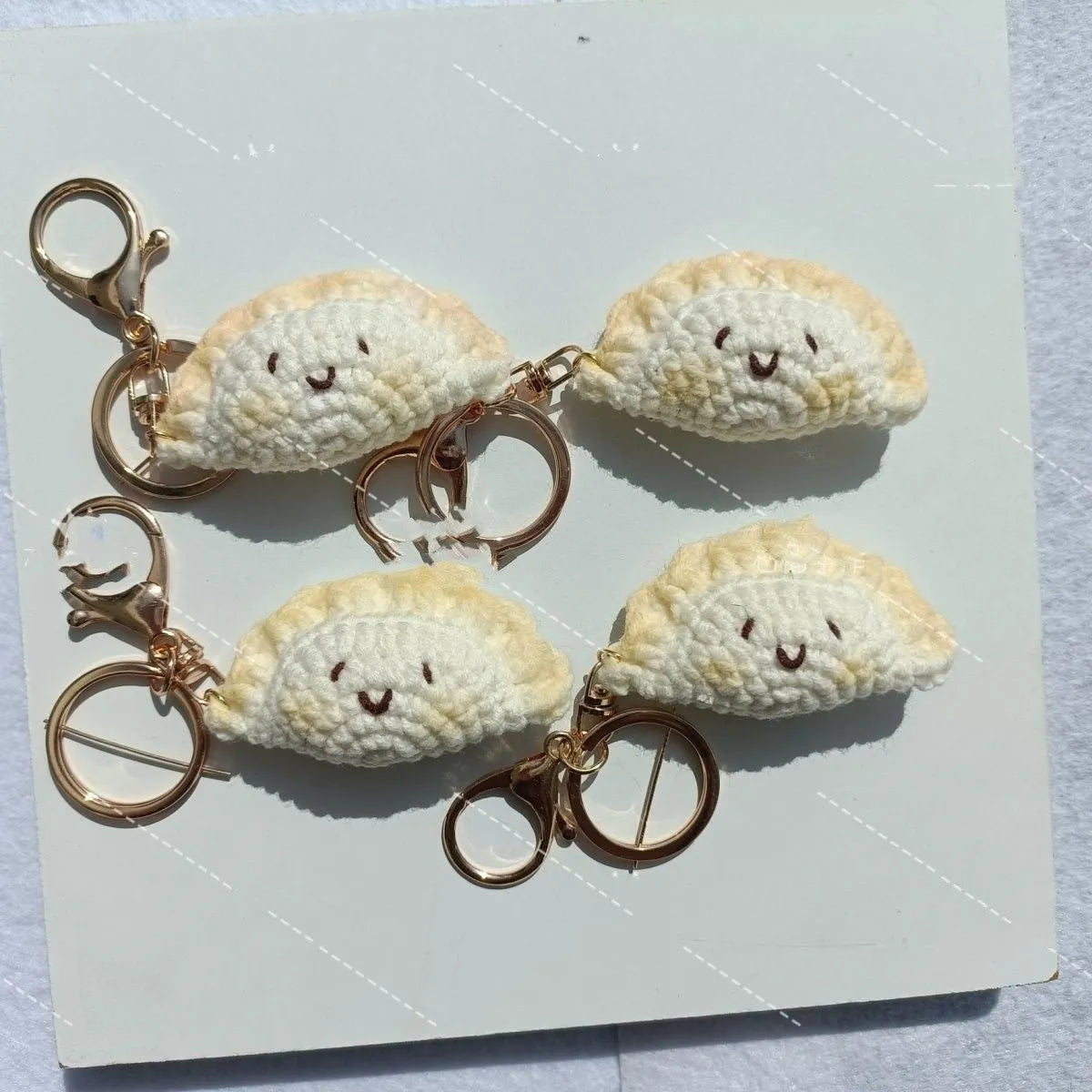Handmade crochet dumpling pendant with Doudou Eye style and attached keychain on white background