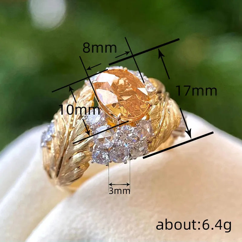Gold-coloured embossed feather fashion ring with geometric shape and inlaid yellow zircon stones.