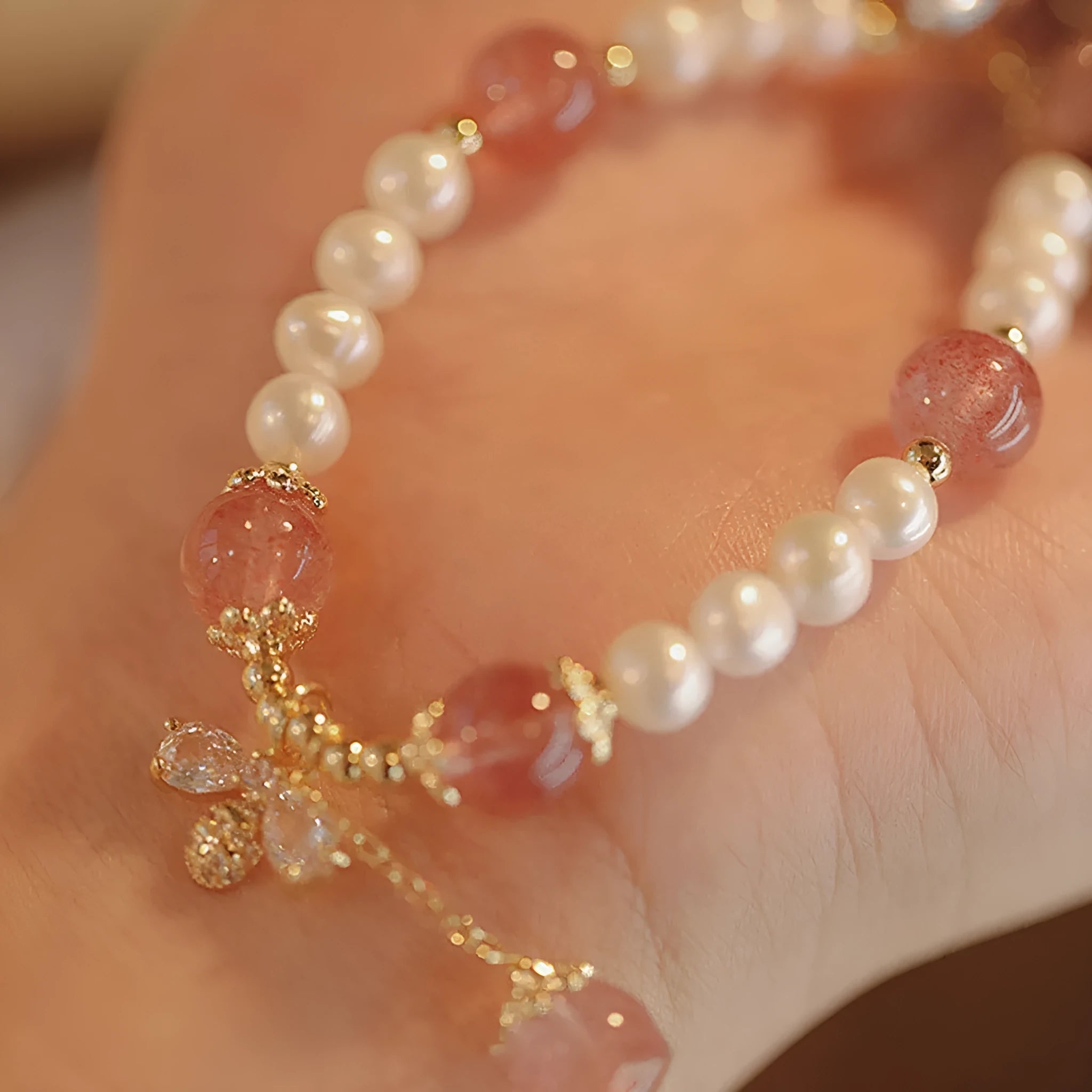 Women's strawberry quartz crystal bracelet with bow clasp closure on wrist
