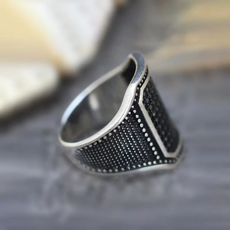 Black alloy ring with copper inlay and zircon stone detailing, shown on a finger.