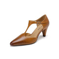 Brown retro women's T-strap sandals with a closed round toe and a short stout heel on a wooden background.