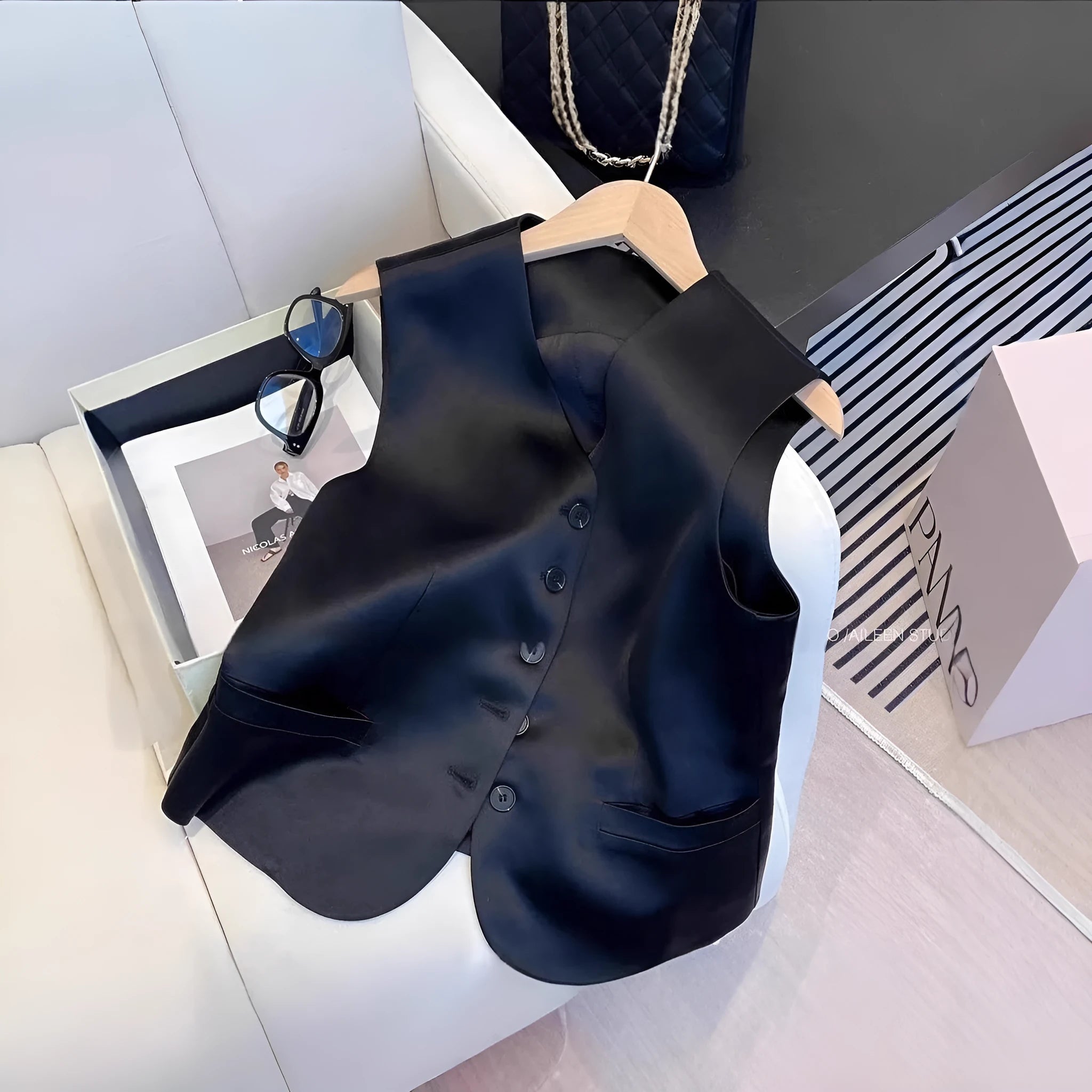 Black satin sleeveless vest for women on a hanger, showing loose fit and splicing detail