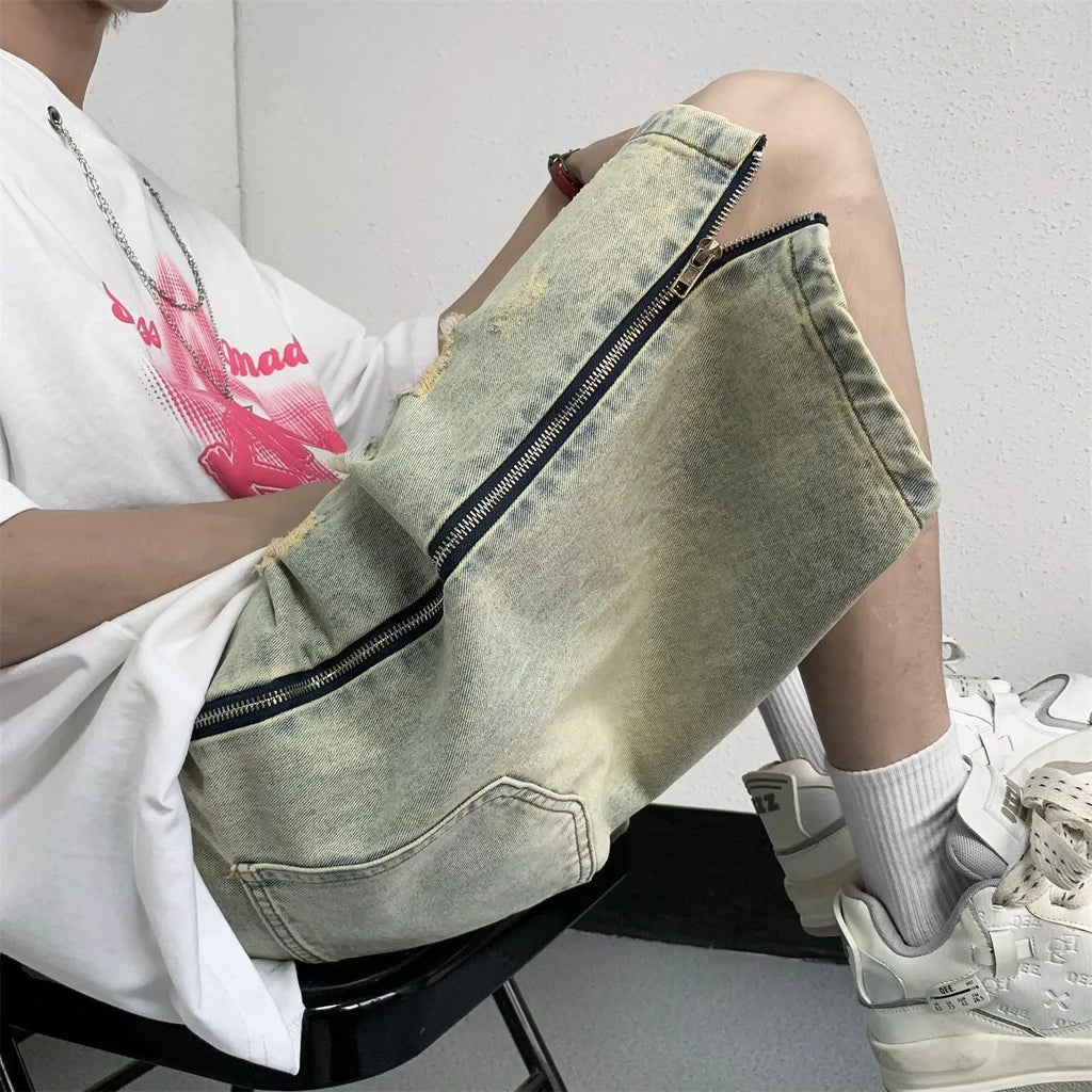 Men's blue loose-fit vintage denim shorts with yellow mud wash and ripped knee details.