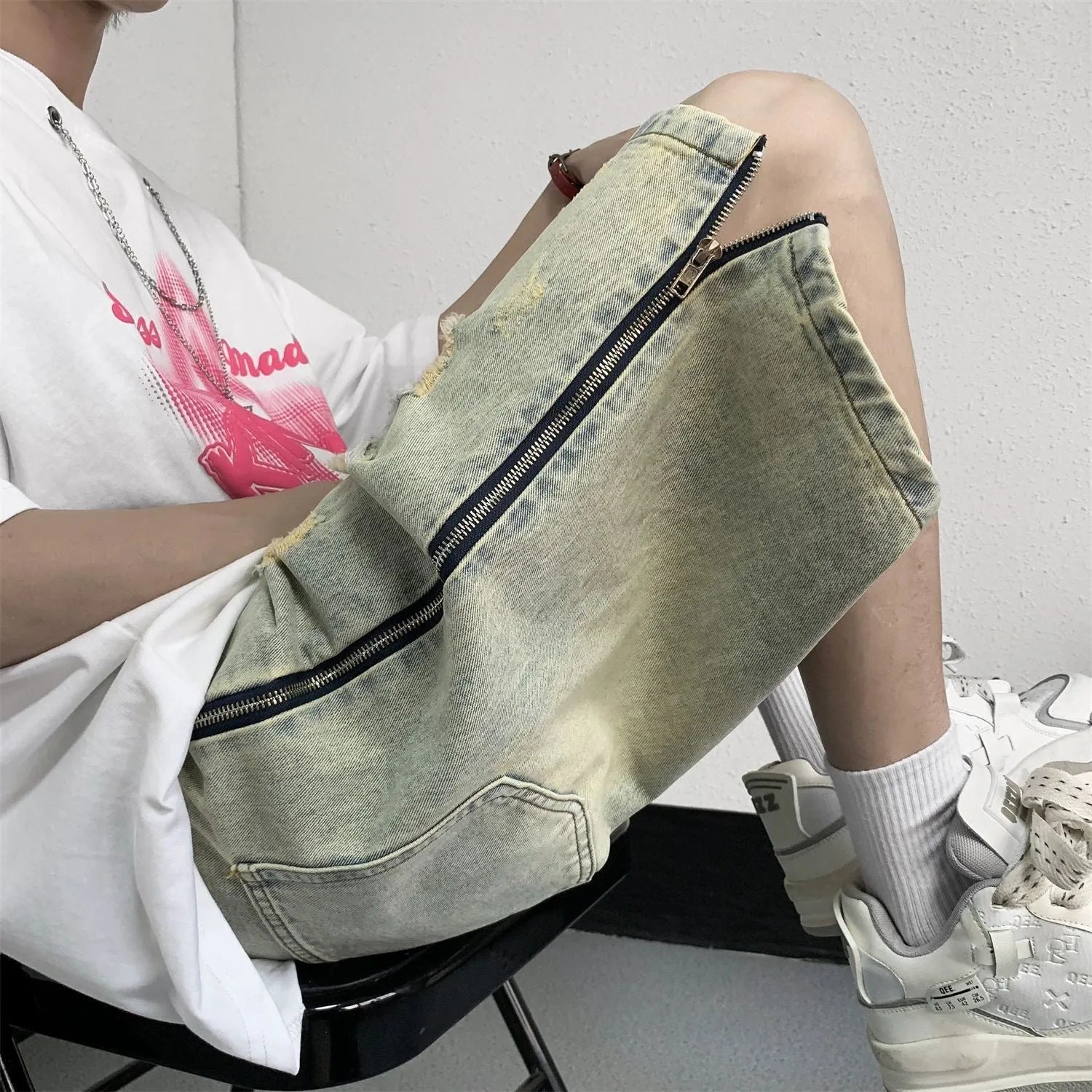 Men's blue loose-fit vintage denim shorts with yellow mud wash and ripped knee details.