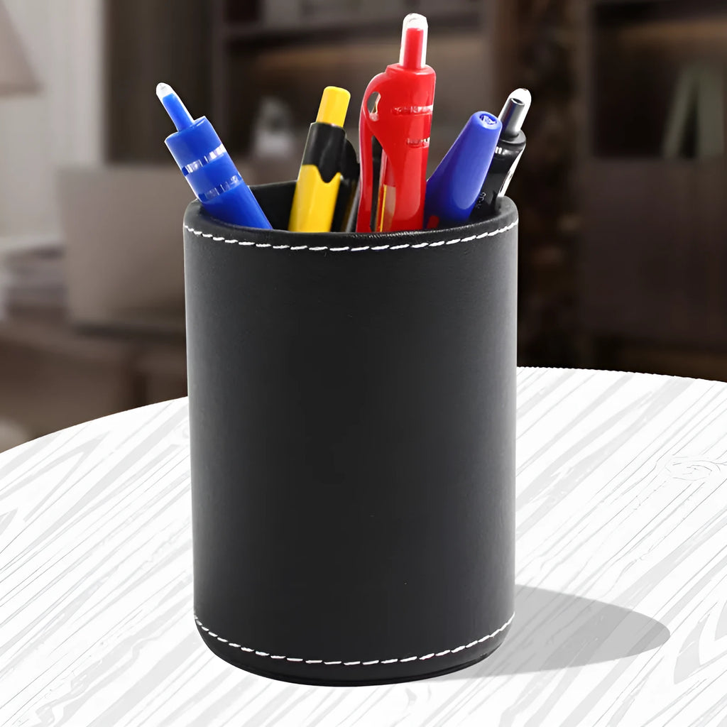 Round black leather pen holder container on desk with pens inside