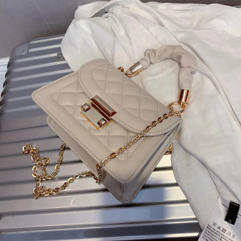 A purple PU leather small square women's crossbody bag with a chain detail and a long strap.