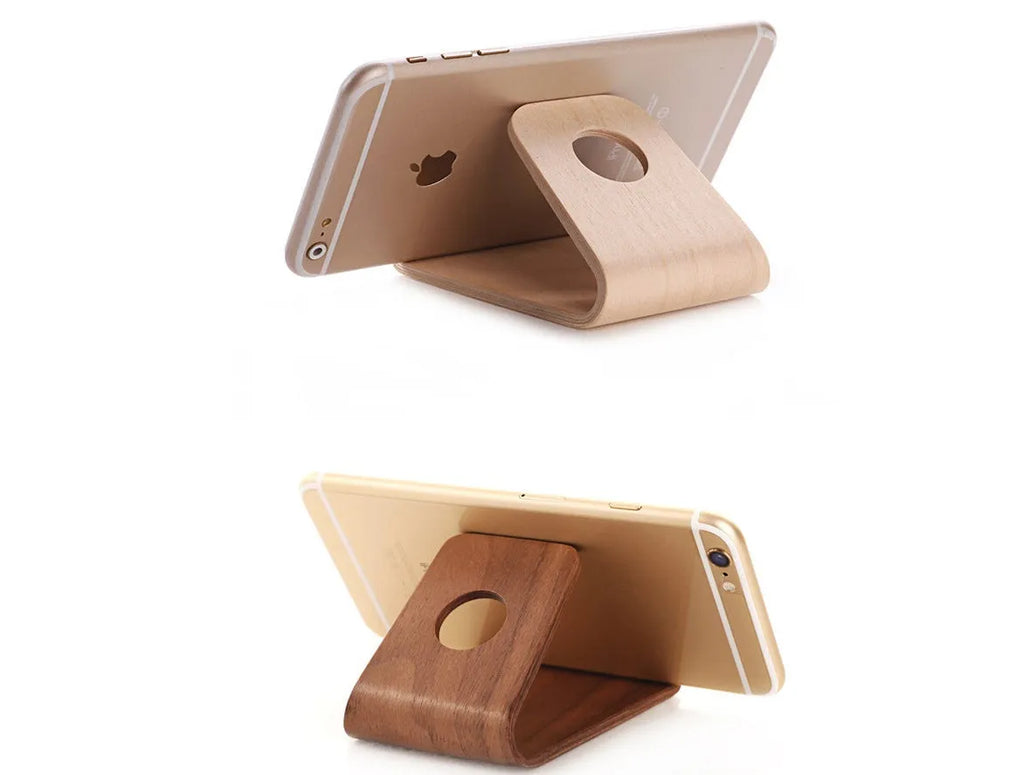 Solid walnut wooden iPhone stand holding a phone at an angle on a desk
