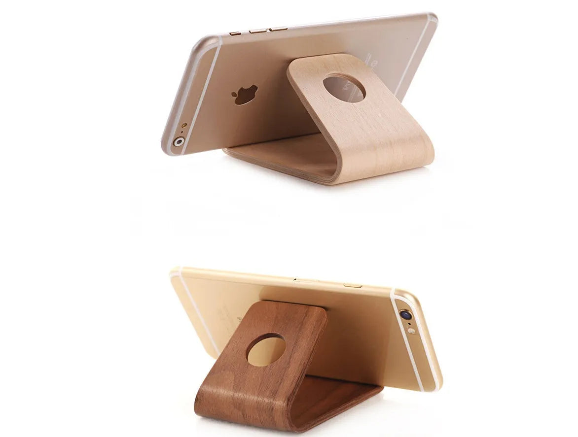 Solid walnut wooden iPhone stand holding a phone at an angle on a desk