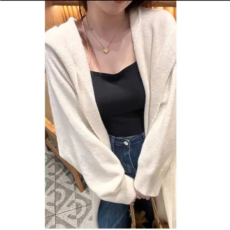 A woman wearing a long, hooded, beige knitted cardigan in a relaxed Korean style.