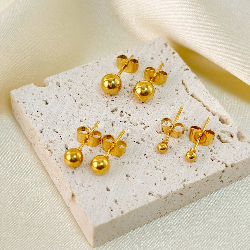 Stainless steel round ball stud earrings on a plain background, showing gold and silver tone options.