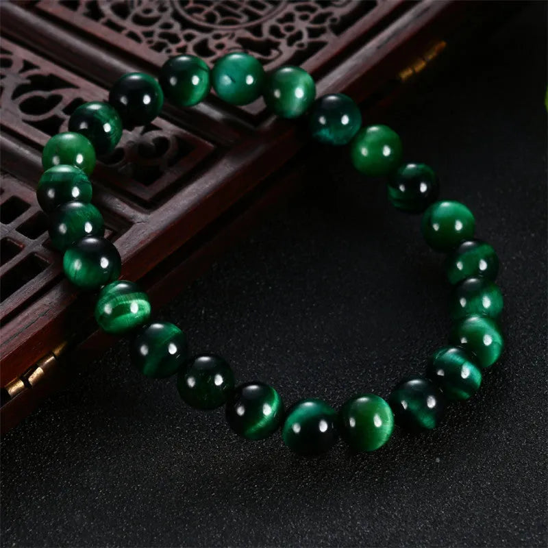 Green tiger eye stone bead bracelet with geometric polished beads on a wrist.