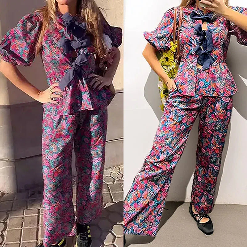 Women's floral print two-piece suit with a tie-neck puff sleeve blouse and straight-leg trousers.